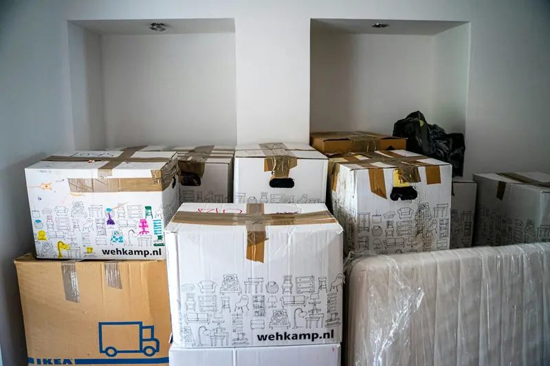 Cajas cerradas con cinta y un bulto envuelto, agrupados en el interior de una vivienda.